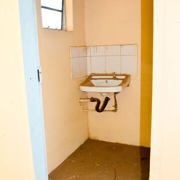A small bathroom with a broken sink and a small window.