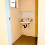 Ein kleines Badezimmer mit einem kaputten Waschbecken und einem kleinen Fenster.