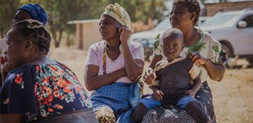 Black women sitting and one has a child on her lap
