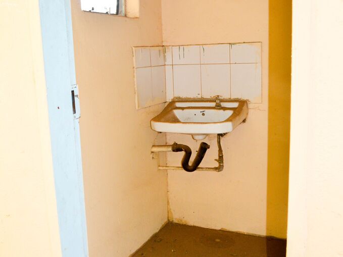 Ein kleines Badezimmer mit einem kaputten Waschbecken und einem kleinen Fenster.